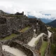 Sayacmarca archaeological site on the Inca Trail, with stone buildings, mountain slopes, and cloud forest scenery around the ruins.