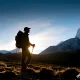 Viajero en el Camino Inca usando una mochila ergonómica de trekking frente a luz de montaña al amanecer o atardecer.